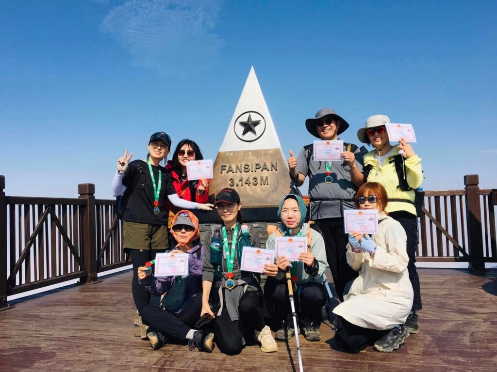 Voyageurs avec un guide Hmong francophone au sommet du mont Fansipan à Sapa, Vietnam