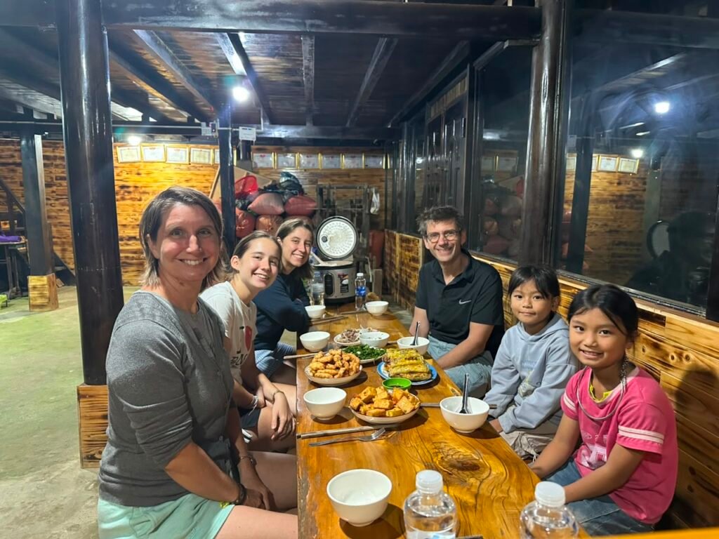 Voyageurs partageant un repas traditionnel avec une famille hmong dans un homestay à Sapa, Vietnam
